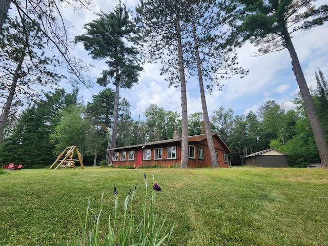 view of front facade with a chimney, a playground, and a front yard