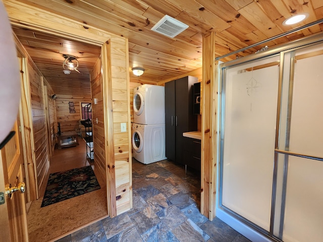 bathroom with wooden walls, wood ceiling, a shower stall, and stacked washing maching and dryer