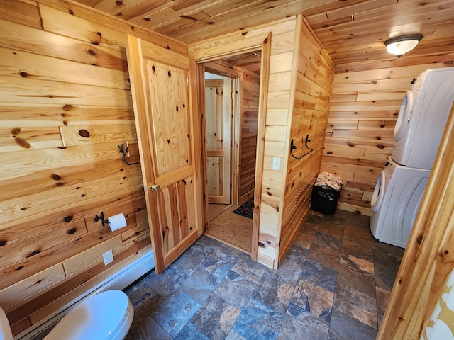 bathroom featuring stacked washer / drying machine, wood walls, wooden ceiling, and stone finish flooring