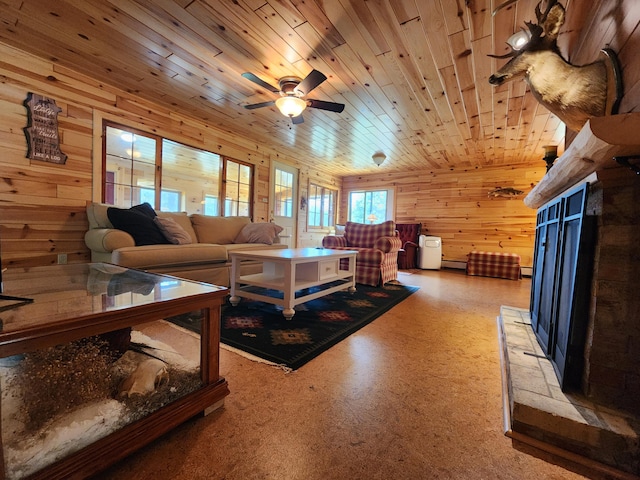 living area featuring a ceiling fan, light floors, a fireplace with raised hearth, wood ceiling, and wood walls