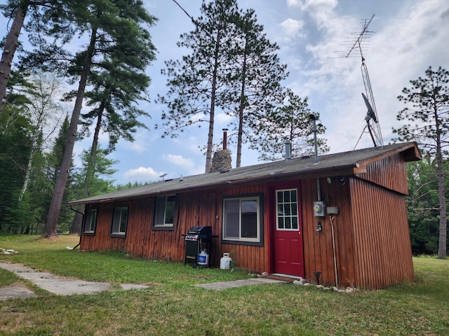 rear view of property featuring a chimney and a yard