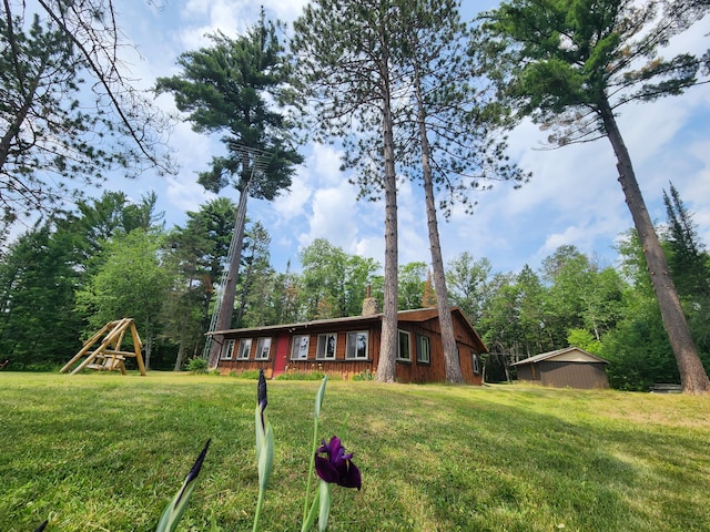 view of front of home with a chimney, a front lawn, and a playground