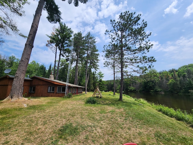 view of yard with a wooded view and a water view