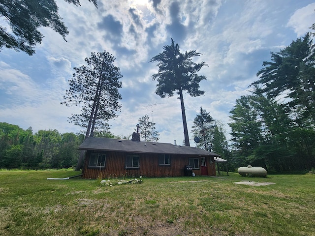 back of house featuring a chimney and a yard