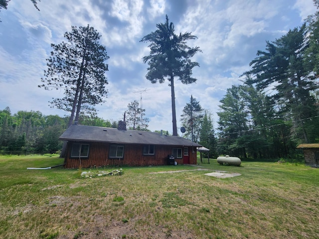 rear view of house featuring a chimney and a yard