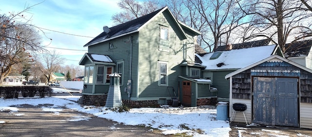 view of snowy exterior featuring a storage unit, an outbuilding, and a chimney