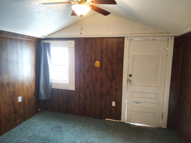 unfurnished room featuring lofted ceiling, carpet floors, and wood walls