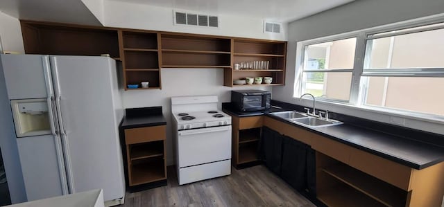 kitchen featuring dark countertops, visible vents, a sink, white appliances, and open shelves