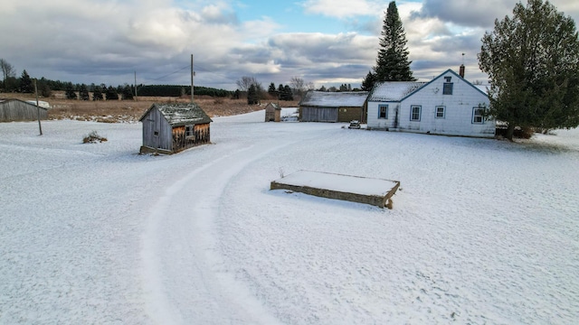 yard layered in snow with a storage shed and an outdoor structure