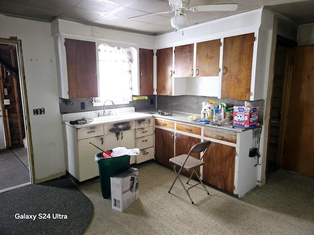 kitchen featuring a sink, decorative backsplash, a ceiling fan, and light countertops