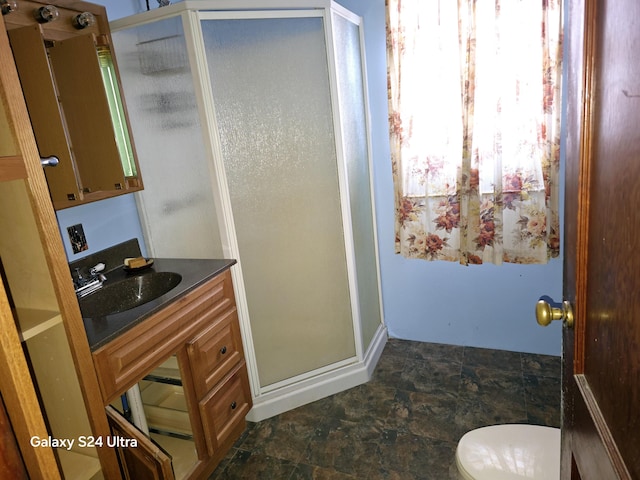 full bath featuring toilet, a stall shower, vanity, and stone finish floor