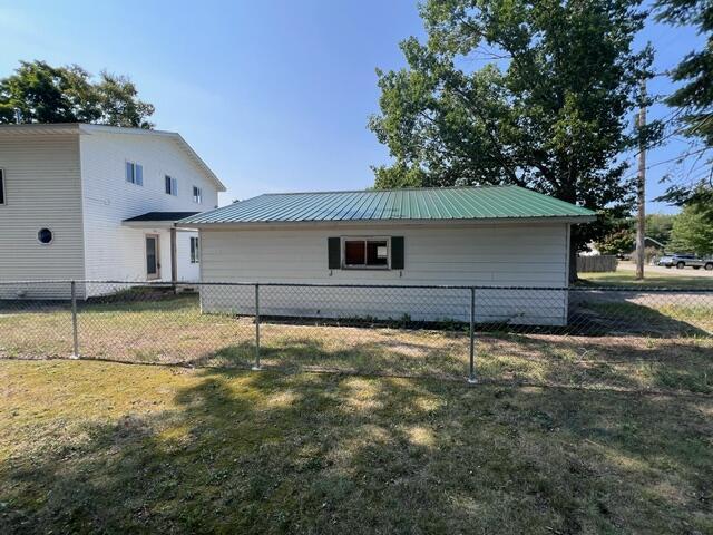 view of side of property with metal roof, a lawn, and fence