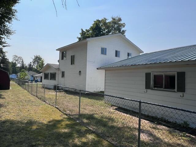 view of property exterior with metal roof, a lawn, and fence