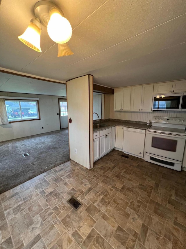 kitchen featuring visible vents, a sink, open floor plan, white appliances, and dark colored carpet