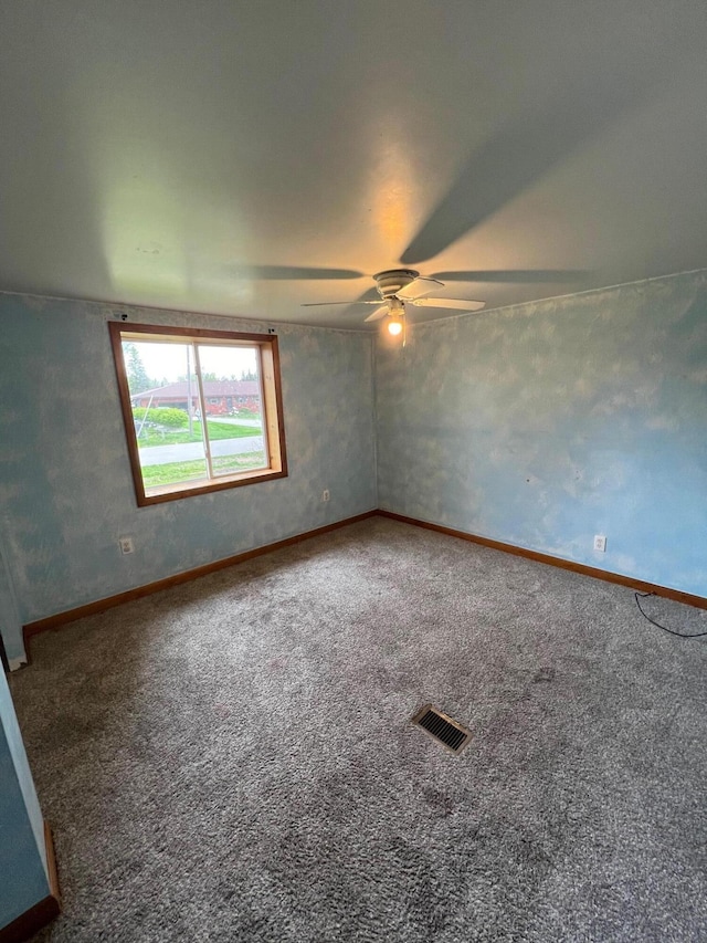 carpeted empty room with visible vents, baseboards, and a ceiling fan