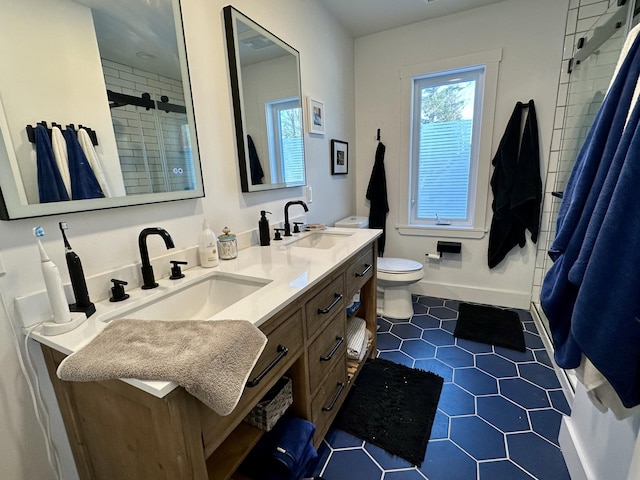 full bath featuring double vanity, a stall shower, toilet, and a sink