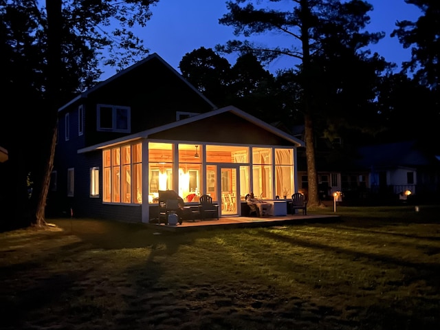 back of house featuring a patio area, a lawn, and a sunroom