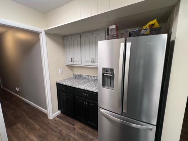 kitchen featuring dark wood-type flooring, stainless steel refrigerator with ice dispenser, white cabinetry, light countertops, and baseboards