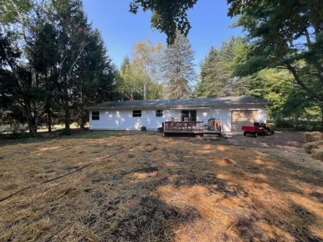 rear view of property featuring a garage and a deck