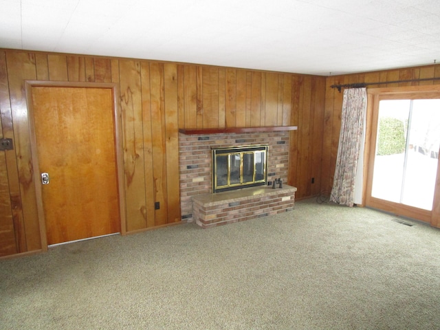 unfurnished living room with visible vents, carpet flooring, a brick fireplace, and wooden walls