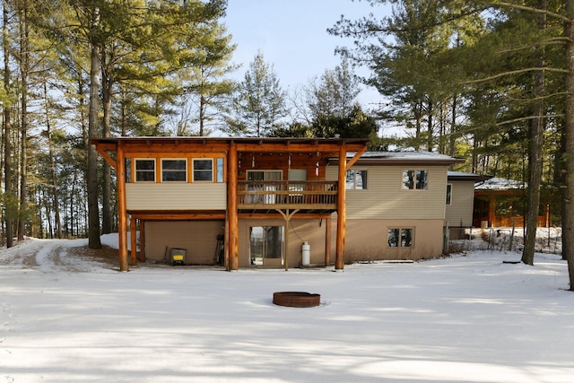 snow covered rear of property featuring a deck and an attached garage