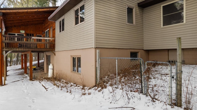 view of snowy exterior with a gate and fence