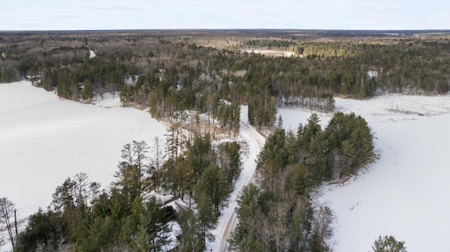 snowy aerial view featuring a wooded view