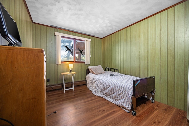 bedroom featuring baseboard heating, wood finished floors, and crown molding