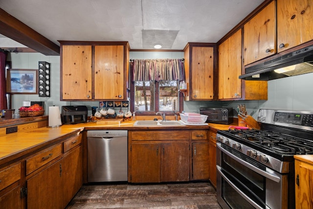 kitchen featuring under cabinet range hood, appliances with stainless steel finishes, brown cabinetry, and a sink