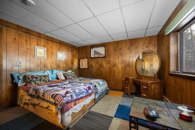 bedroom with wood walls, a baseboard heating unit, and a paneled ceiling