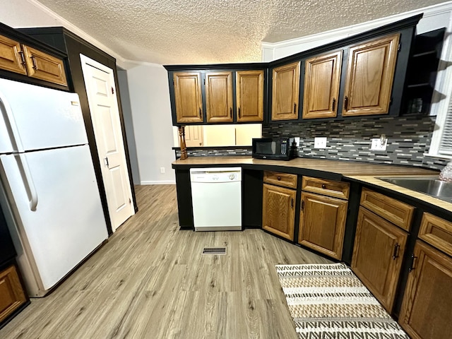 kitchen with light wood-type flooring, ornamental molding, a sink, white appliances, and decorative backsplash