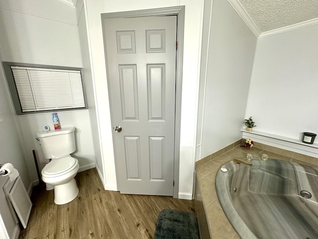 full bathroom with crown molding, toilet, a whirlpool tub, wood finished floors, and a textured ceiling