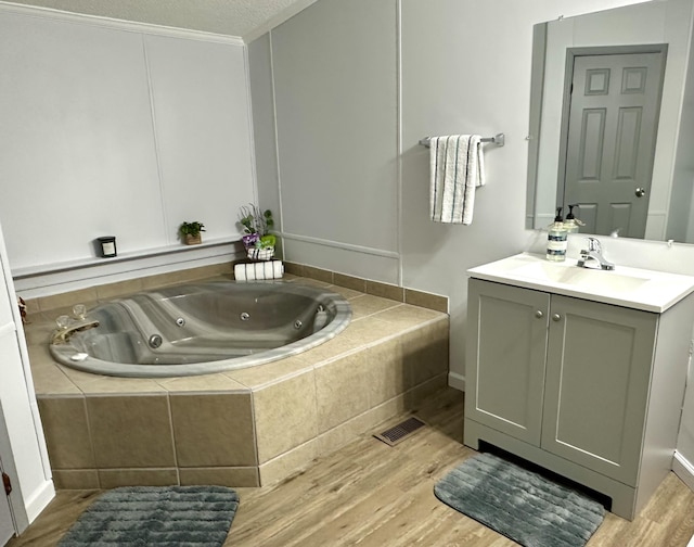 full bath with vanity, wood finished floors, a whirlpool tub, and a textured ceiling