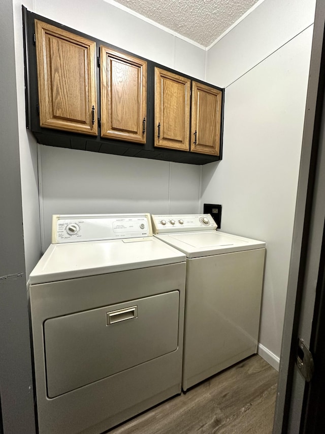 clothes washing area with wood finished floors, cabinet space, independent washer and dryer, and a textured ceiling