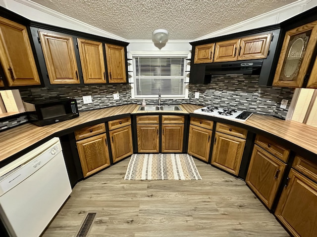 kitchen with white appliances, wooden counters, light wood-style flooring, a sink, and exhaust hood