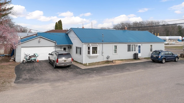 rear view of property featuring aphalt driveway and metal roof