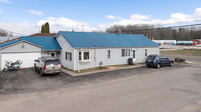 view of front of property featuring aphalt driveway, a garage, and metal roof