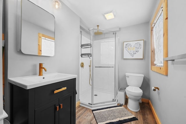 full bath with vanity, wood finished floors, baseboards, a stall shower, and toilet