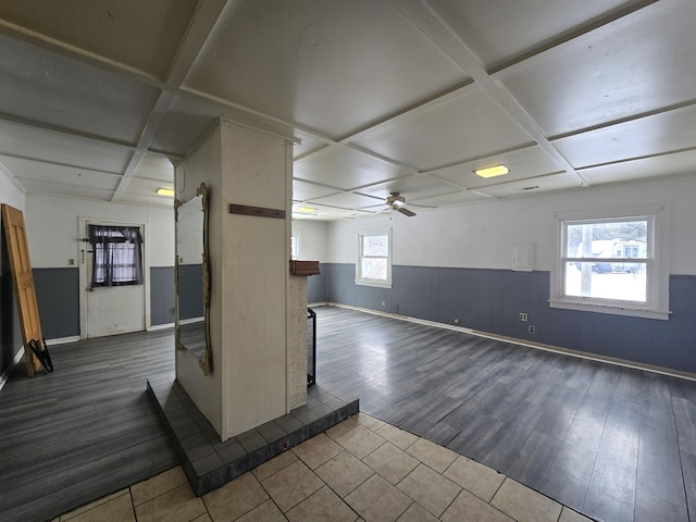 below grade area featuring ceiling fan, a barn door, baseboards, dark wood-style flooring, and wainscoting