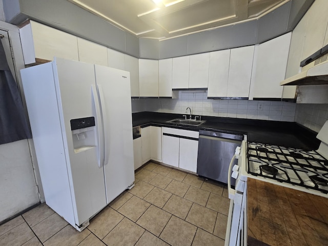 kitchen featuring dark countertops, white appliances, white cabinets, and a sink