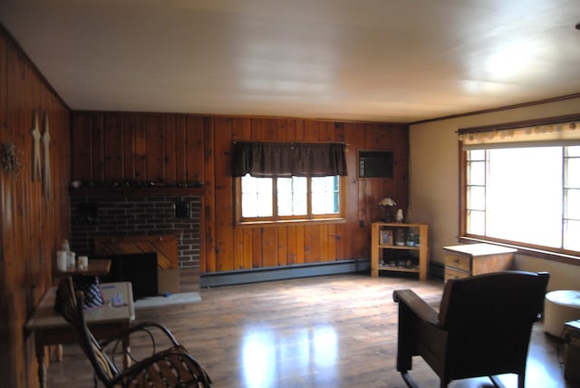 living area featuring a baseboard heating unit, plenty of natural light, wood finished floors, and a fireplace