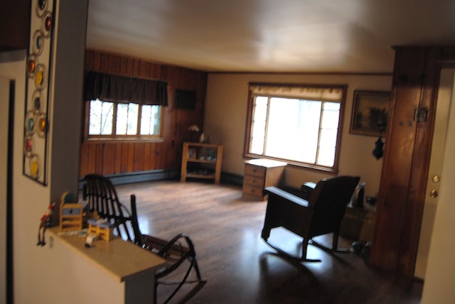 sitting room featuring wood finished floors, wood walls, and a baseboard radiator