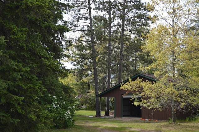 704 10th St, Mio, MI 48647 - view of green lawn featuring an outdoor structure and a detached garage