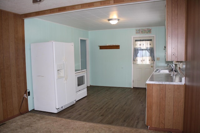 kitchen with a sink, dark wood-style floors, white appliances, brown cabinetry, and light countertops