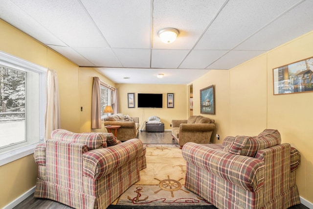 living room with a drop ceiling and baseboards