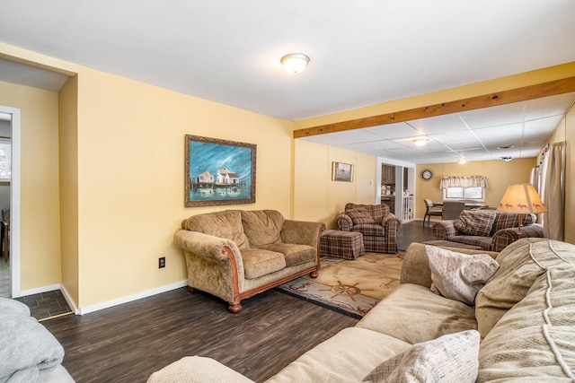 living room featuring a drop ceiling, baseboards, and wood finished floors