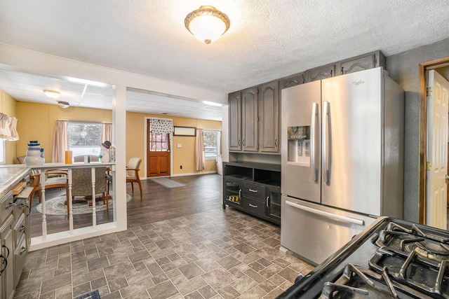 kitchen featuring an AC wall unit, baseboards, stainless steel refrigerator with ice dispenser, and stone finish flooring