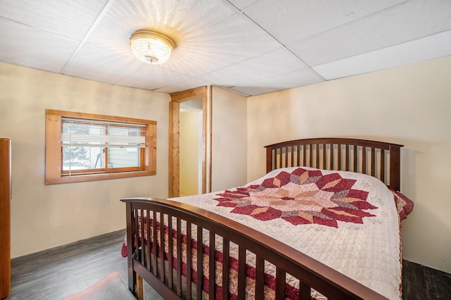 bedroom with wood finished floors and a drop ceiling