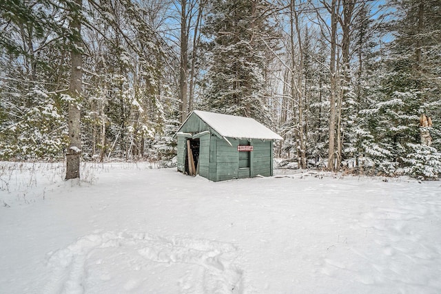 snow covered structure with a storage shed and an outdoor structure