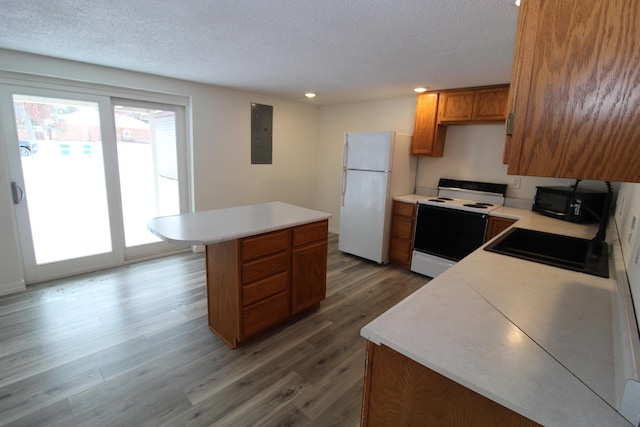 kitchen with light wood-style flooring, a sink, a kitchen island, white appliances, and light countertops